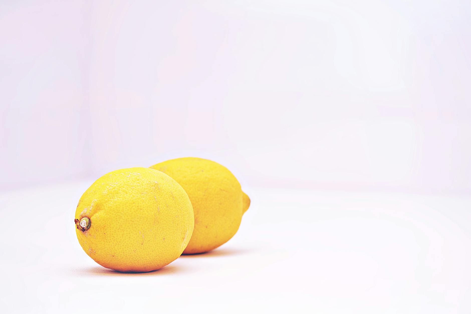 Blue vibrator surrounded by flowers and citrus on a bright yellow background