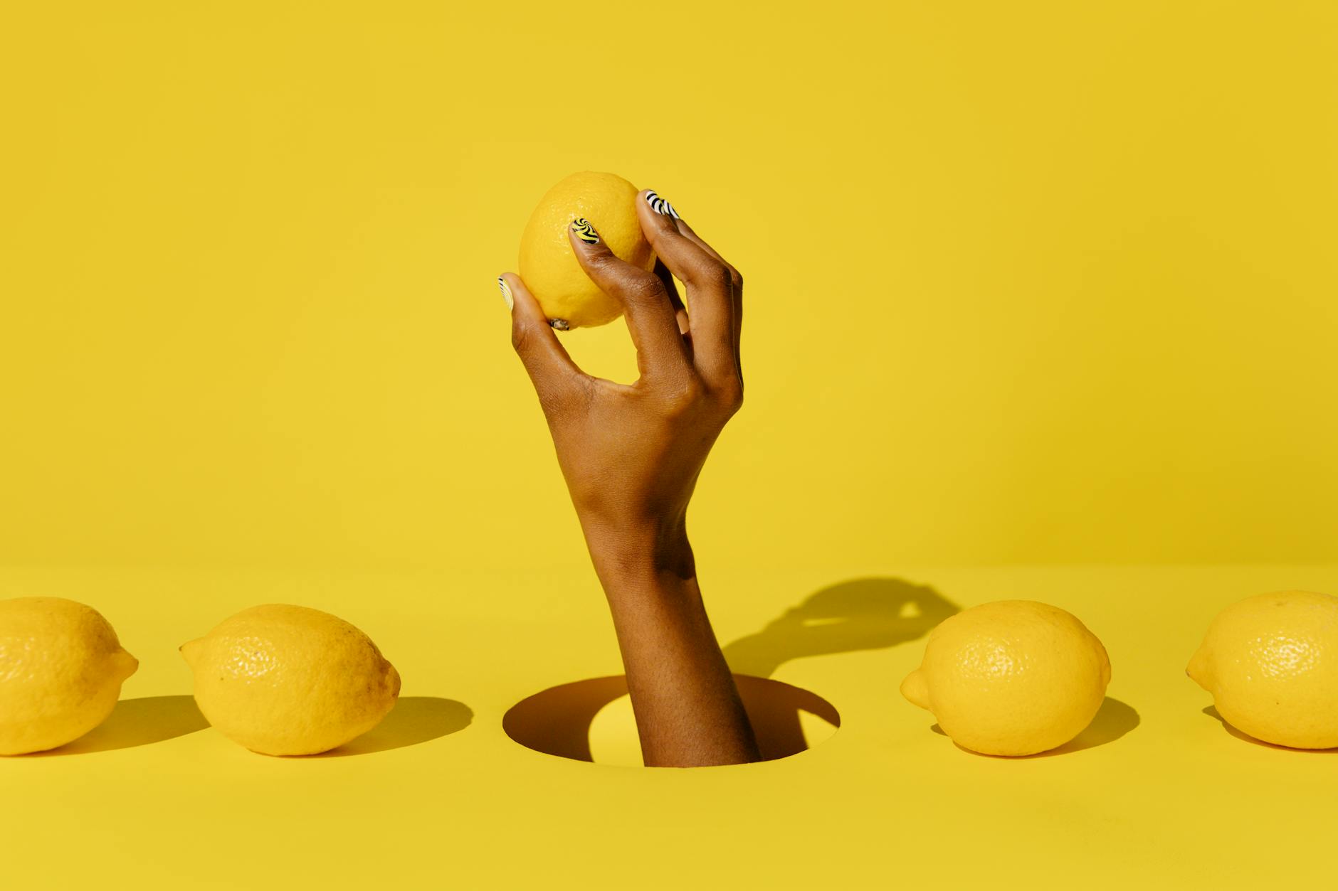 A fresh lemon held in cupped hands against a yellow background, symbolizing the citrus appeal of Hellanancyslem's lemon vibrators