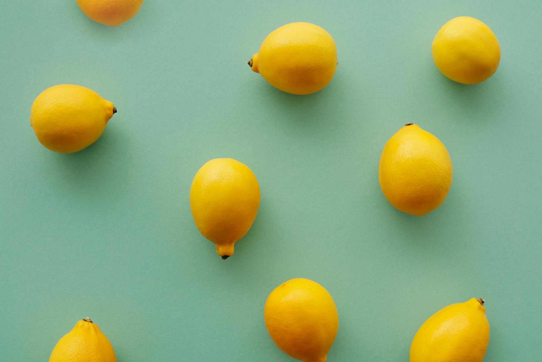Bright yellow lemons arranged on a pastel green background, symbolizing fresh discovery and the bright sensation of lemon vibrators