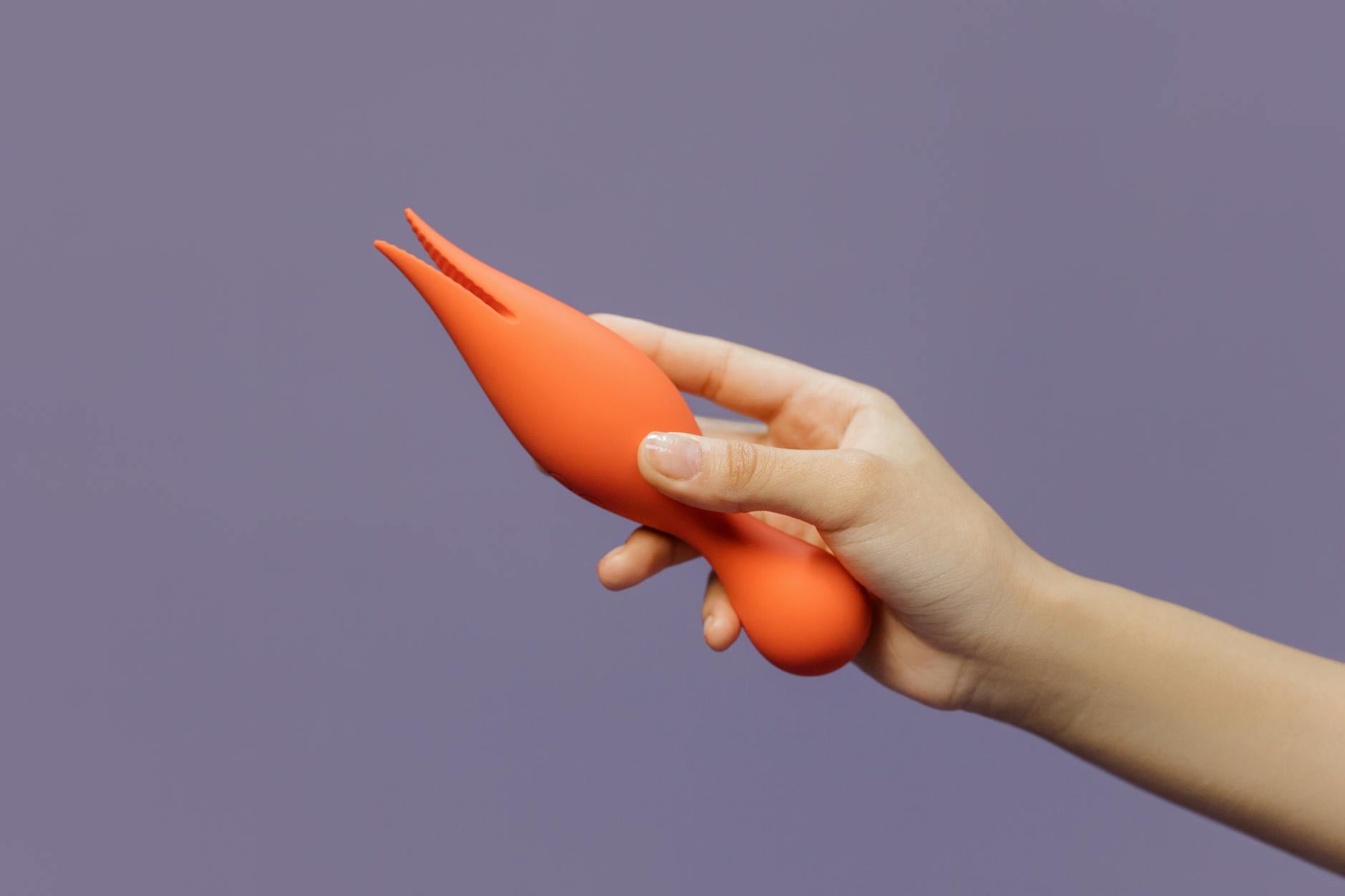 Hand holding a lemon-colored clitoral vibrator against a minimalist backdrop, emphasizing modern sensuality and design.