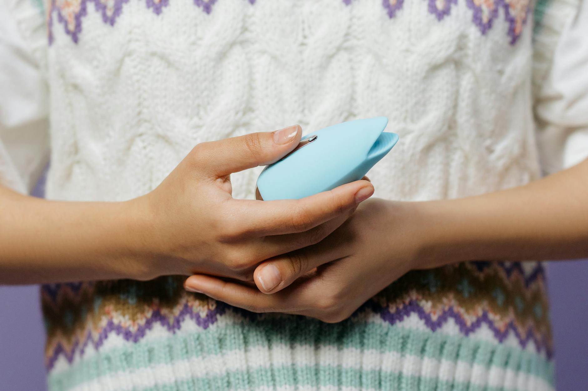 Person holding blue and pink clitoral vibrators in contemplative moment
