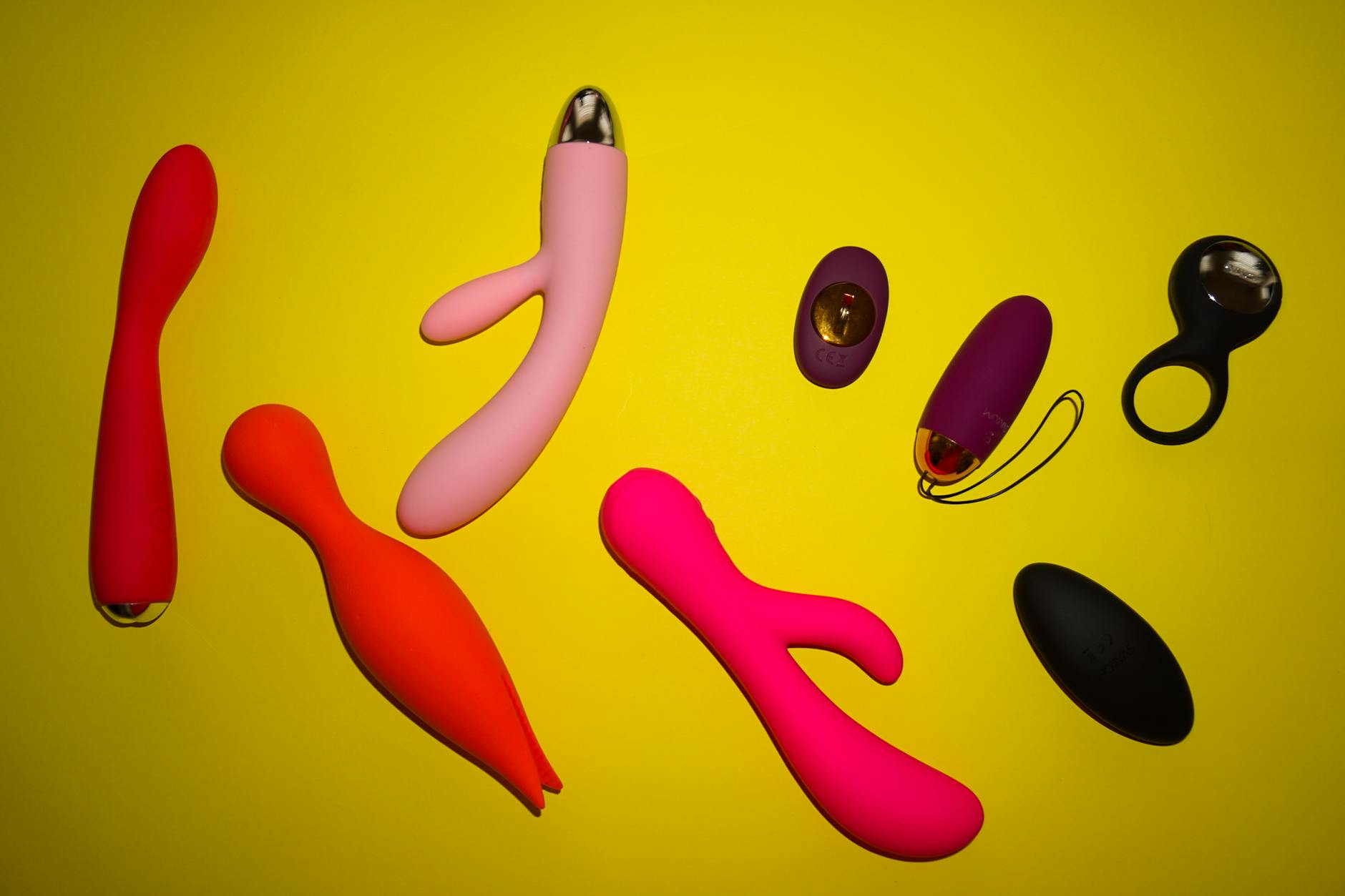Arrangement of colorful lemon clitoral vibrators and adult toys on a yellow surface
