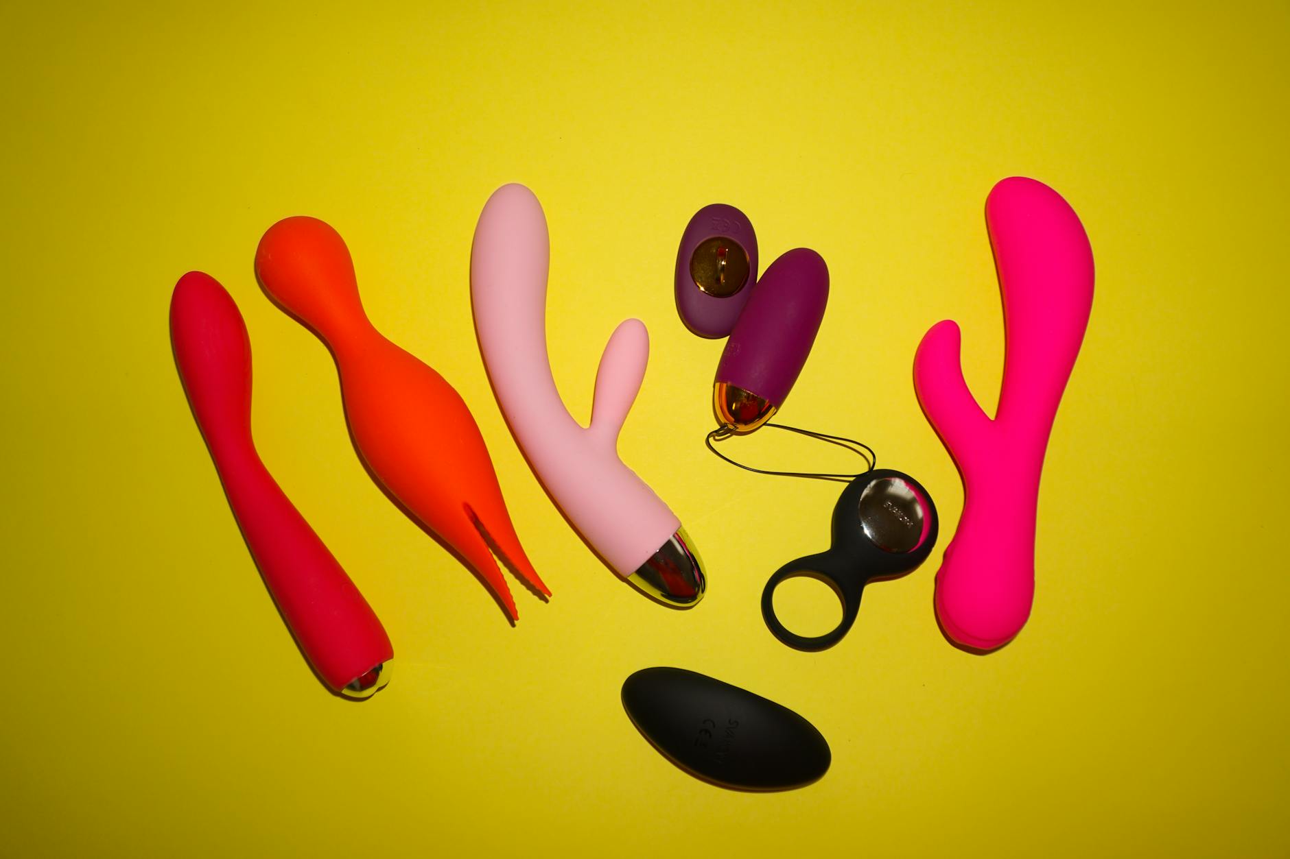 Woman holding blue and pink silicone vibrators in a contemplative manner