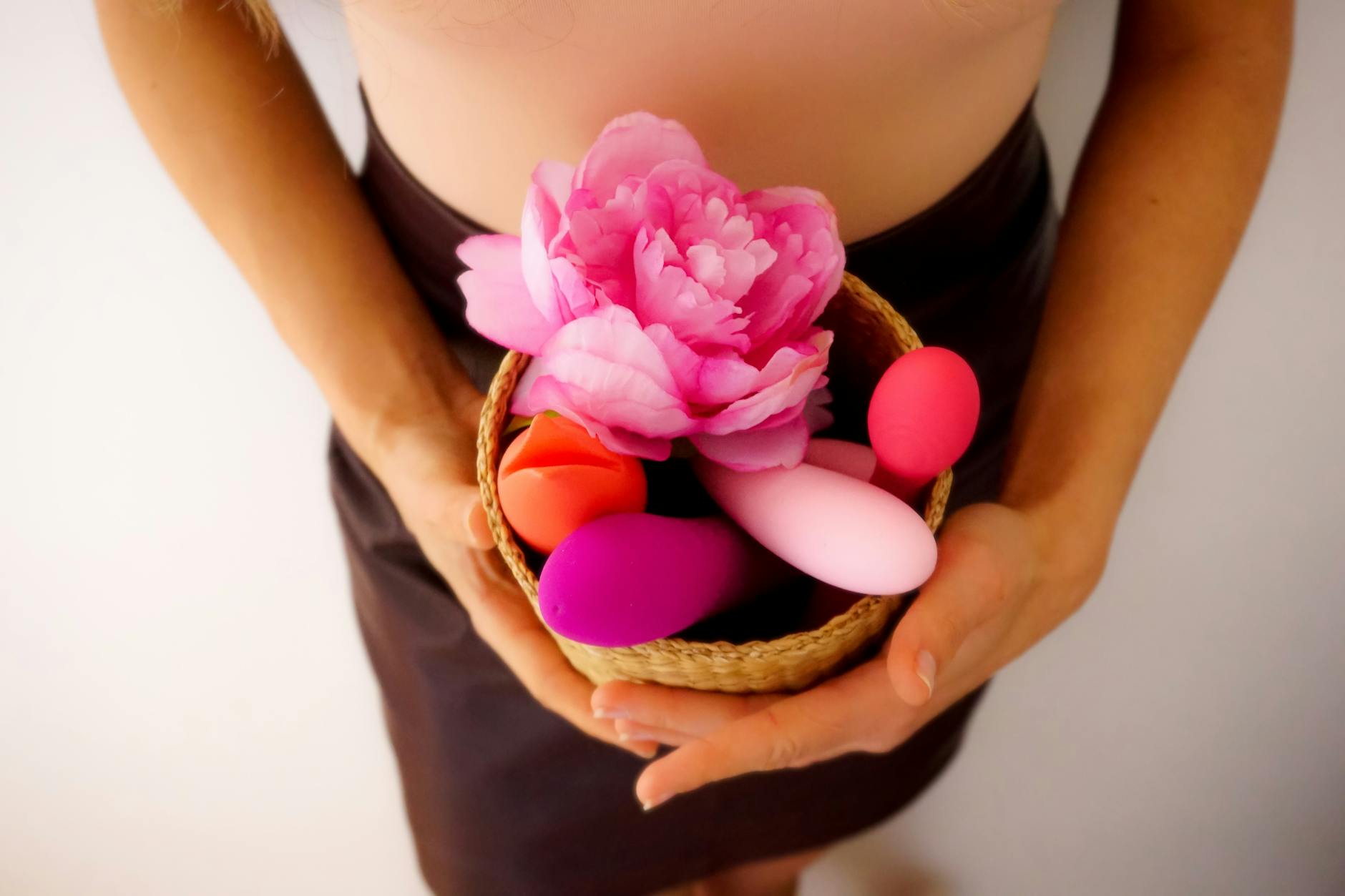 Hand holding an orange suction vibrator against a minimalistic purple backdrop